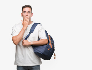 Handsome young man holding backpack cover mouth with hand shocked with shame for mistake,...