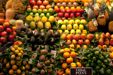 La Boqueria market in the Barcelona, Spain. Stall of avocado, pineapple, apple, kiwi, orange and other exotic fruits at world famous marketplace.