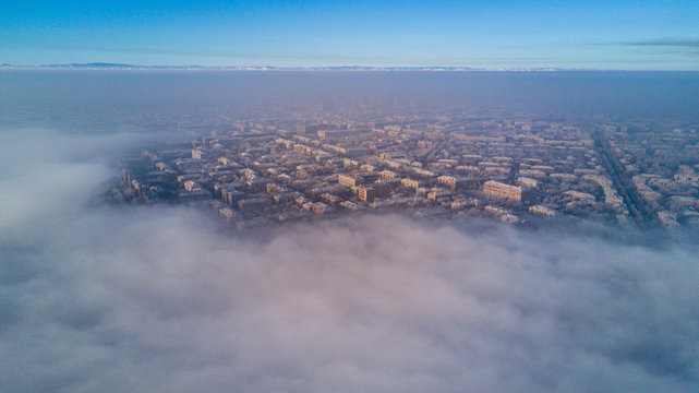 Aerial photo of city Magnitogorsk with the looming fog in the winter evening, Low lying cloud over the city
