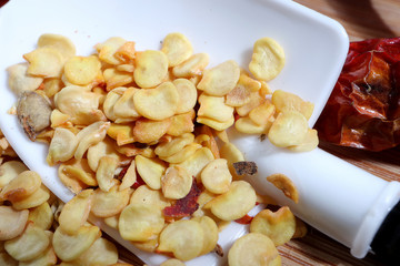 Macro shot of Chilli pepper seed in white shovels on wooden board background. Foods and agricultural concept.