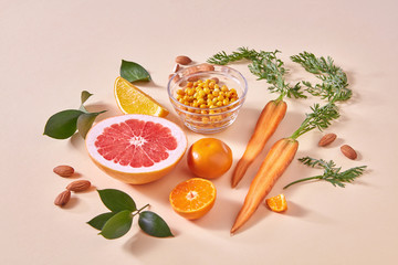 Natural freshly picked fruits- citrus fruits, carrots, sea buckthorn berries on an orange paper.