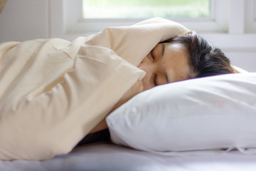 Fototapeta na wymiar young woman face sleeping while lying in white bed in Sunbeam dawn.