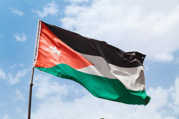 Flag of Jordan waving on wind over sky