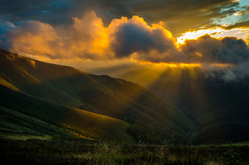 Sunset at Borzhava ridge near mountain Velykyi Verch in Ukrainian Carpathians. The rays of the sun are coming through the clouds. Sunset in the mountains in Ukraine.