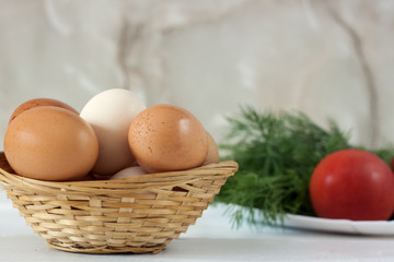 Raw eggs in a wicker basket on a white table