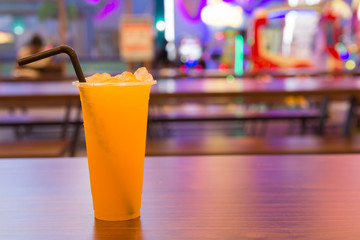 Fresh orange juice in glass on wood table in the mall