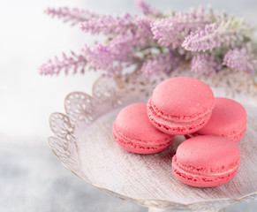 Obraz na płótnie Canvas Pink macaroons on a vintage plate and flowers. Pastel colored.