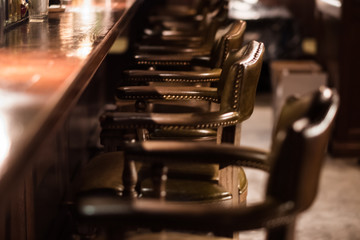 Bar design in classic vintage style. Oak wooden bar counter, comfortable chairs with leather upholstery and cooper rivets. Luxury interior. Great place for relax after work. 