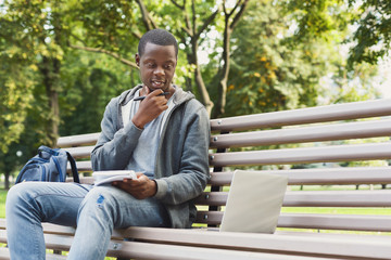 Fototapeta premium Thoughtful african-american student studying with laptop