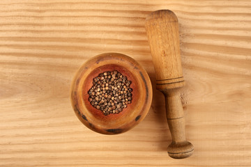 An overhead photo of black peppercorns in a mortar with a pestle, with copy space