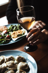 Female hand with glass of wine and food in the background