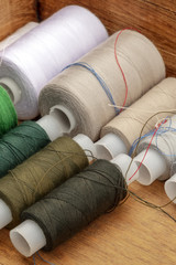 Fototapeta na wymiar A closeup photo of sewing thread spools, beige and brown, in a wooden box
