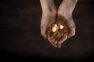 Dirty child's hands with a handful of small coins, poverty symbol, with copy space