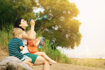 mother and children play in nature. bubble