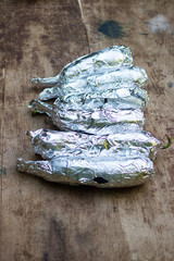 Eggplants wrapped into foil paper ready to cook, grill, roast, fry on open fire. Vegan lunch, vegetarian dinner, healthy organic food diet.