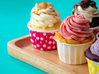 Colorful of homemade cupcake in wooden Tray on green background.