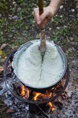 Cook gomi (mamaliga porridge) - popular dish from Samegrelo region made of white coarse cornmeal, butter and salt in big kettle on open fire. Georgian traditional food.