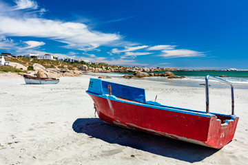 Fototapeta na wymiar A red fishing boat on the white sand of the beach at Paternoster in South Africa