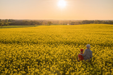 Top view.A farmer and his son in a rapeseed field at sunset 