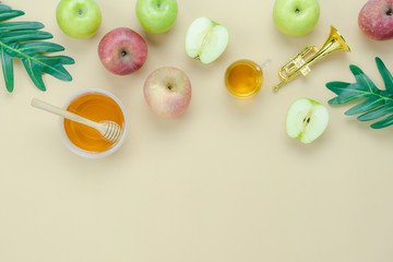 Table top view aerial image of decorations Jewish holiday the Rosh Hashana background concept.Flat lay of variety apple & honey bee and green left on modern rustic yellow paper.Free space for design.