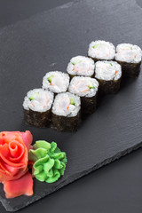 Japanese restaurant, sushi roll on black slate plate.