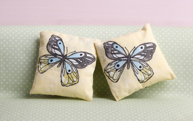 Two  pillows with blue butterfly on spotted green background