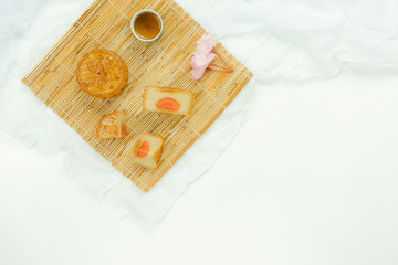 Table top view aerial image of decorations Chinese Moon Festival background concept.Flat lay sweet cake & tea with cloth on modern rustic white wooden wallpaper.Free space for creative design mock up