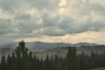 Cloudy evening in Carpathian forest and mountain landscape with small houses. foggy forest and cloudy sky in the Ukrainian mountains