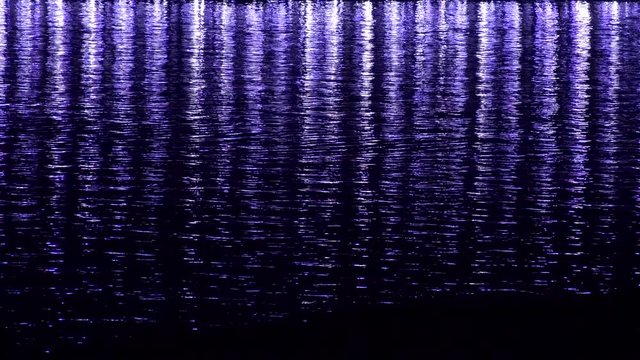 Purple glares on the water by night. An artistic light reflections.