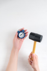 hands of a young girl holding a blue alarm clock on a white  background