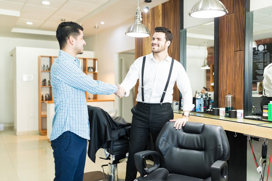 Barber Greeting Customer With A Handshake In Shop
