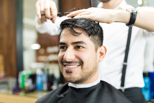 Smart Client Smiling While Stylist Cutting His Hair In Salon