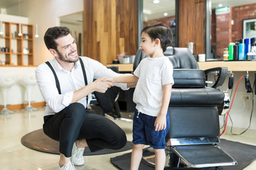 Smiling Male Barber Greeting Little Customer In Salon