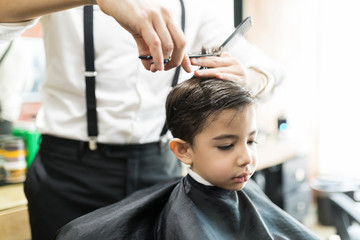 Boy Having Haircut With Comb And Scissors At Barber Shop