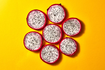 Flat lay view of background from round slices of Dragon fruit or Pitaya on a yellow background.