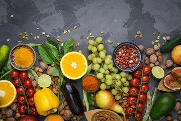 Healthy food background, frame of organic food. Ingredients for healthy cooking: vegetables, fruits, nuts, spices. Balanced diet food on a dark black background. Top view. Copy space on top