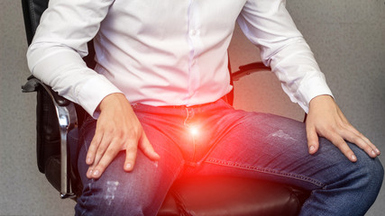 A man sits in an office chair, sore groin, crotch, prostatitis, close-up