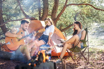 Party, camping of men and women group at forest. They relaxing, singing a song against green grass. The vacation, summer, adventure, lifestyle, picnic concept