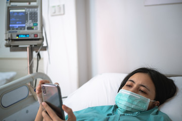 Obraz premium young woman patient lay on bed in hospital and use smartphone