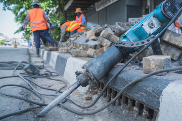 labors are constructing pedestrian walkways; workers building and installing stone tiles to build footpath