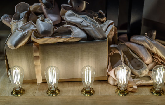 Many pairs of used ballet shoes in cardboard box. Pointe in different condition from new to very shabby old. Horizontal.