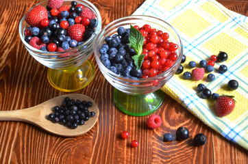 berries of red-blue color on a dark brown wooden background healthy food