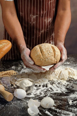 Obraz premium Man preparing buns at table in bakery, Man sprinkling flour over fresh dough on kitchen table