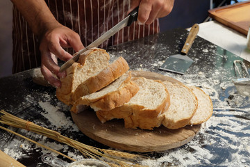 Man preparing buns at table in bakery, Man sprinkling flour over fresh dough on kitchen table