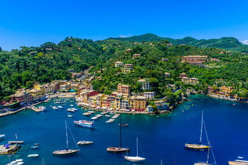 Fototapeta na wymiar Portofino, Italy - colorful houses and yacht in little bay harbor. Liguria, Genoa province, Italy. Italian fishing village with beautiful sea coast landscape in summer season.