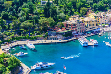 Fototapeta na wymiar Portofino, Italy - colorful houses and yacht in little bay harbor. Liguria, Genoa province, Italy. Italian fishing village with beautiful sea coast landscape in summer season.