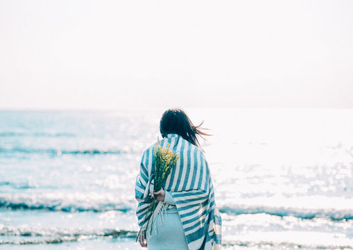 海で花を持つ女性