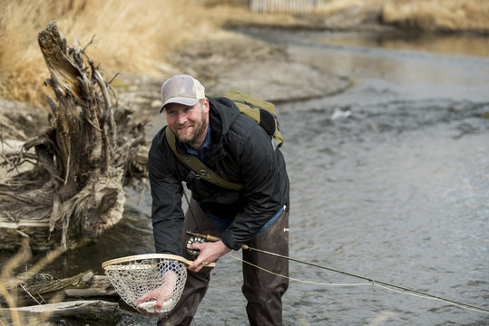 Man removing fish from butterfly fishing net while standing in river