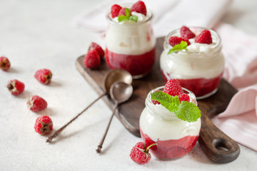 Jars of natural white yogurt with berry sauce decorated with fresh raspberry and mint