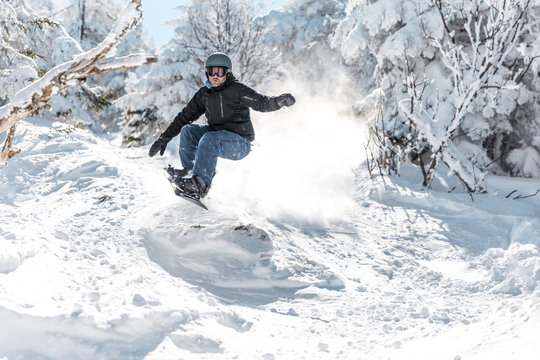 Man snowboarding on snow against trees during winter